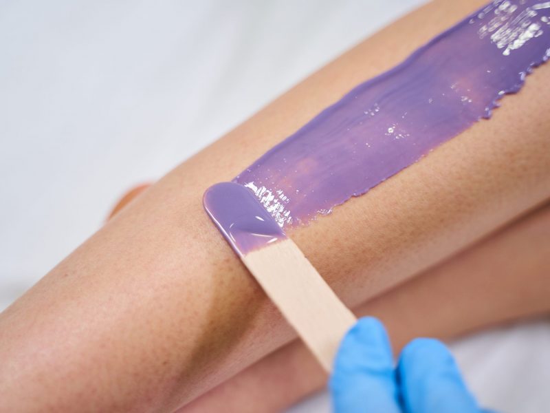 Female person holding wooden stick while working with wax for depilation